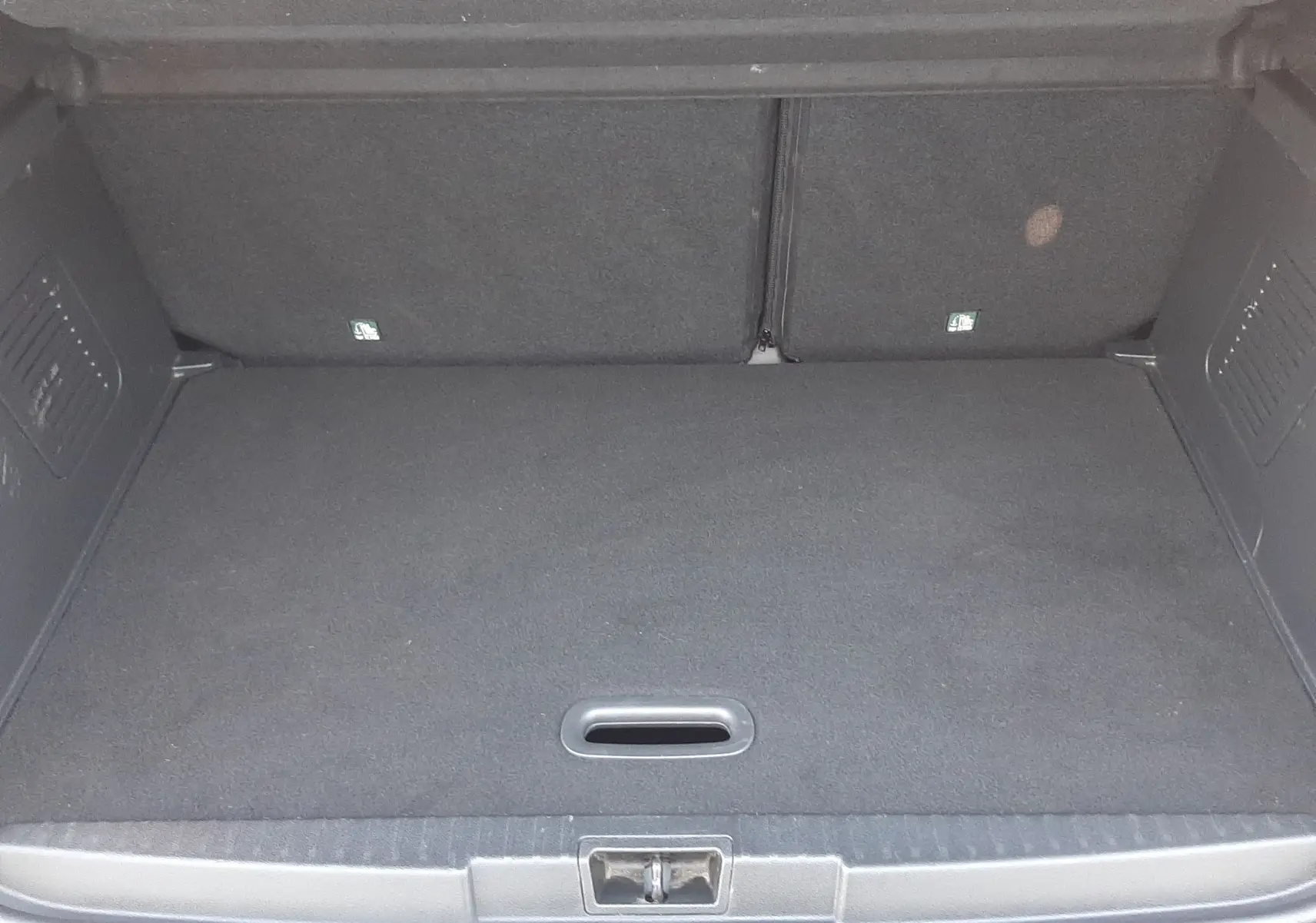 Coffre ouvert vu de l'arrière du Renault Captur blanc nacré avec intérieur noir, montrant un espace de chargement vide.