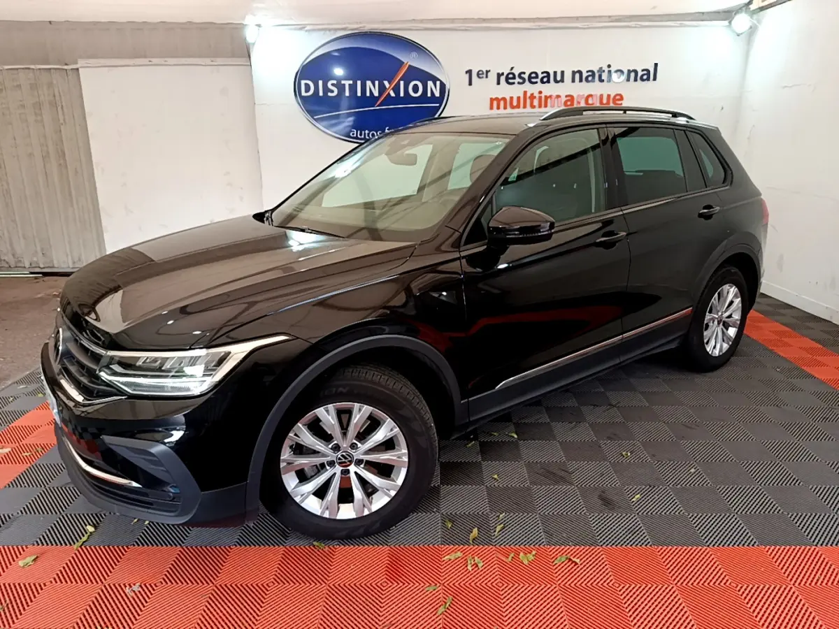 Volkswagen Tiguan noir 2021 vu en 3/4 avant droit dans un showroom avec sol noir et rouge.