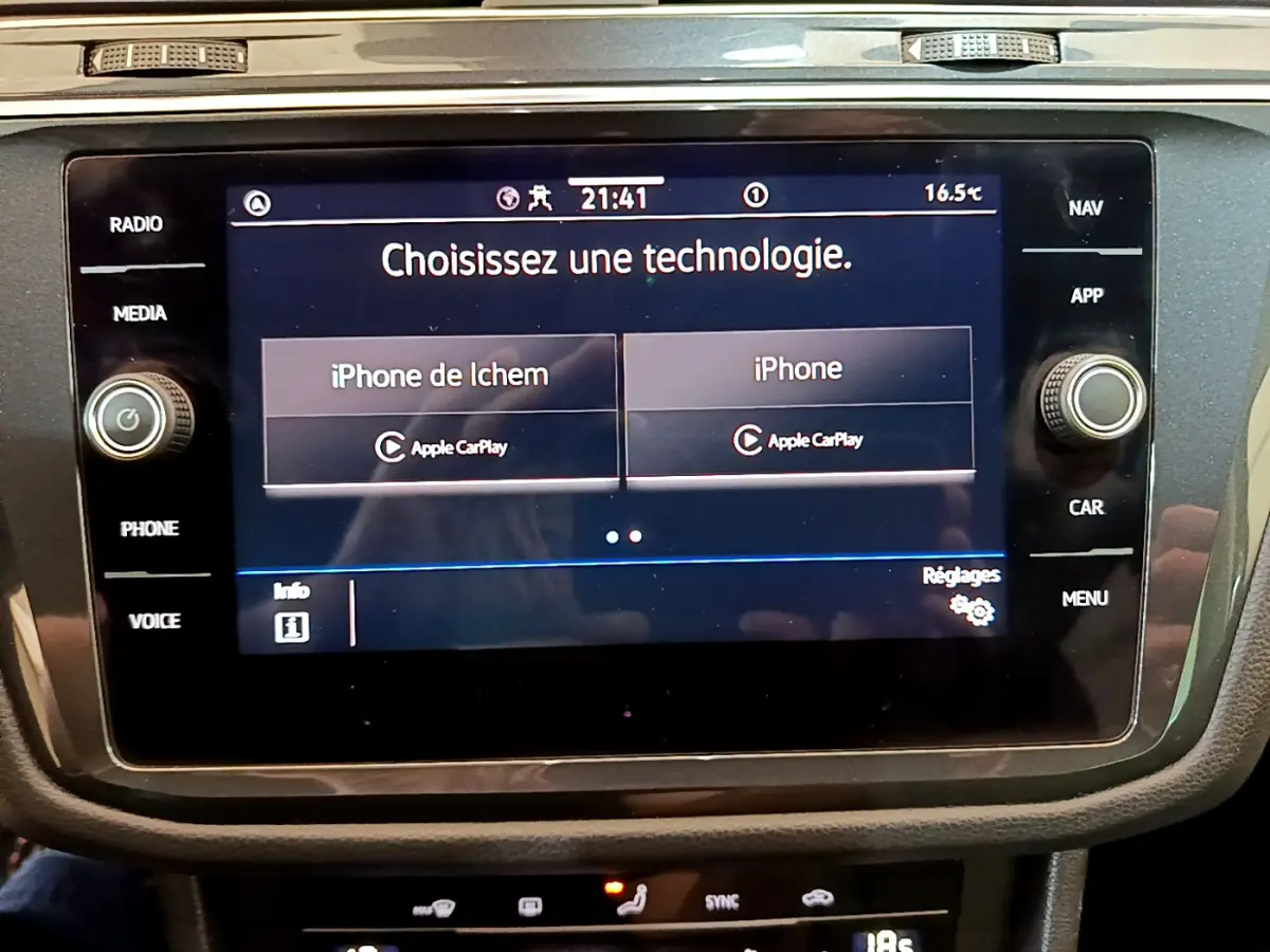 Écran tactile central du Volkswagen Tiguan 2.0 TDI noir, affichant le choix Apple CarPlay pour deux iPhone.