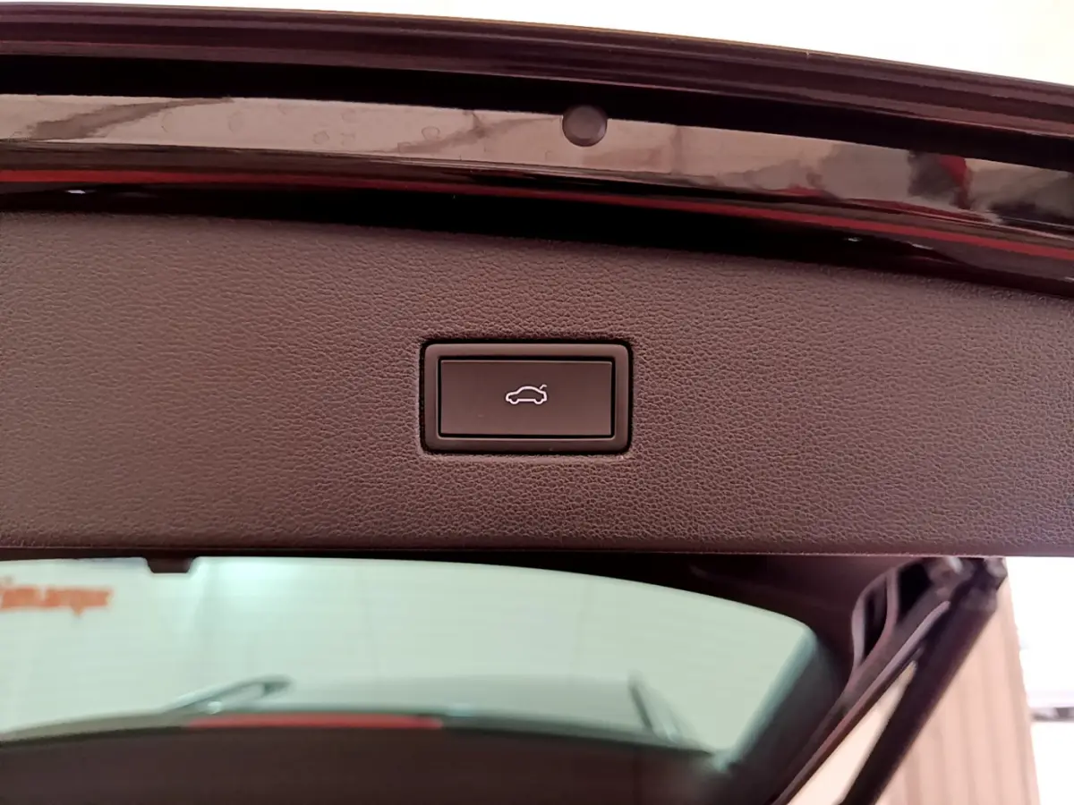 Bouton d'ouverture électrique du coffre sur la partie intérieure du hayon d'un Volkswagen Tiguan noir, vue en gros plan.