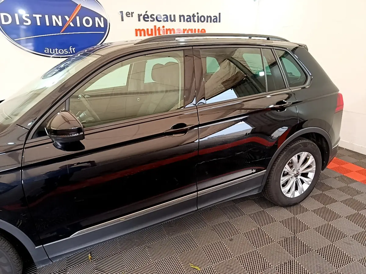 Vue latérale droite d'un Volkswagen Tiguan noir 2021 stationné en intérieur sur sol à damier rouge et noir.