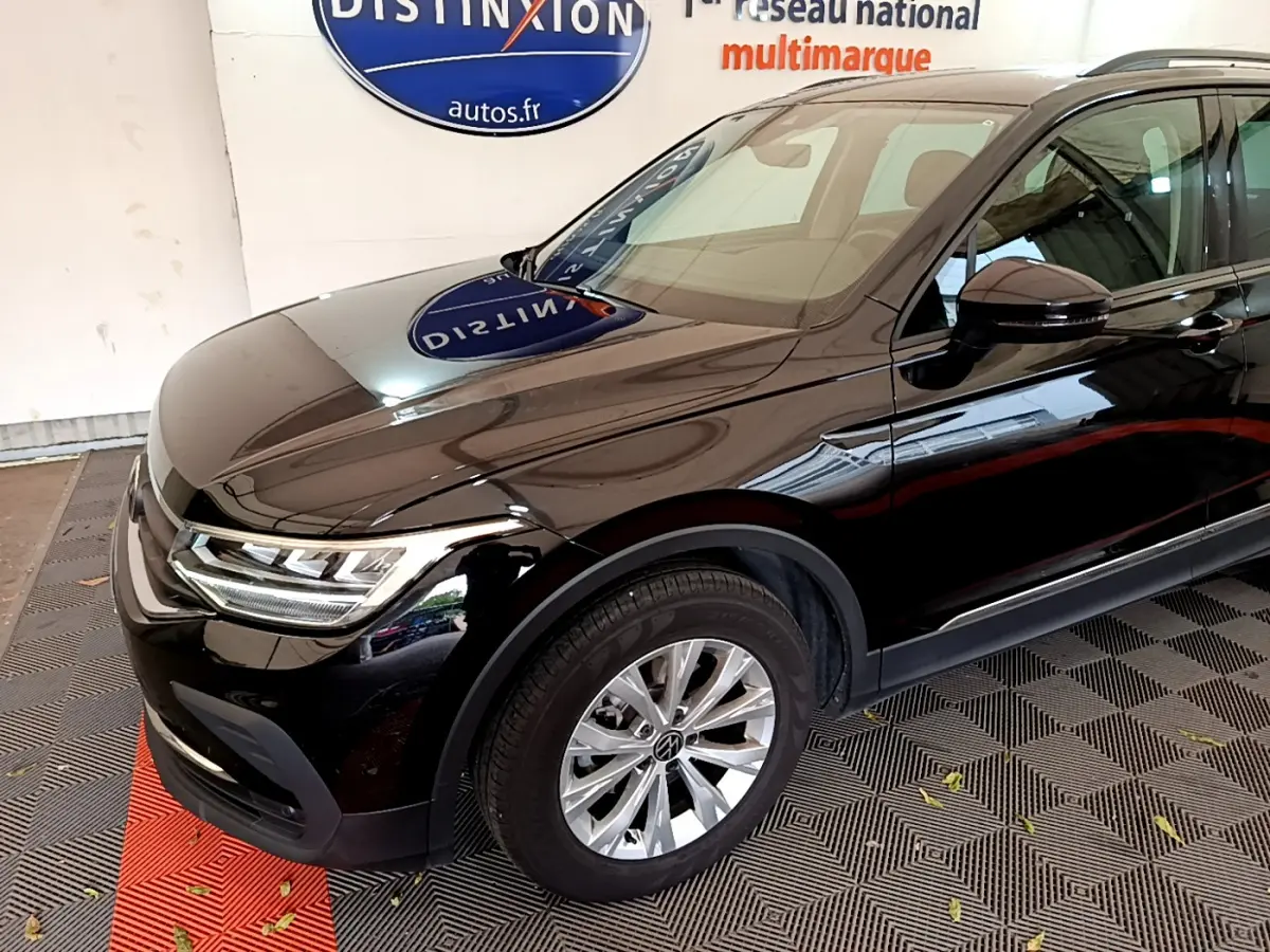 Vue 3/4 avant côté gauche d'un Volkswagen Tiguan noir brillant avec jantes alliage et phares LED.