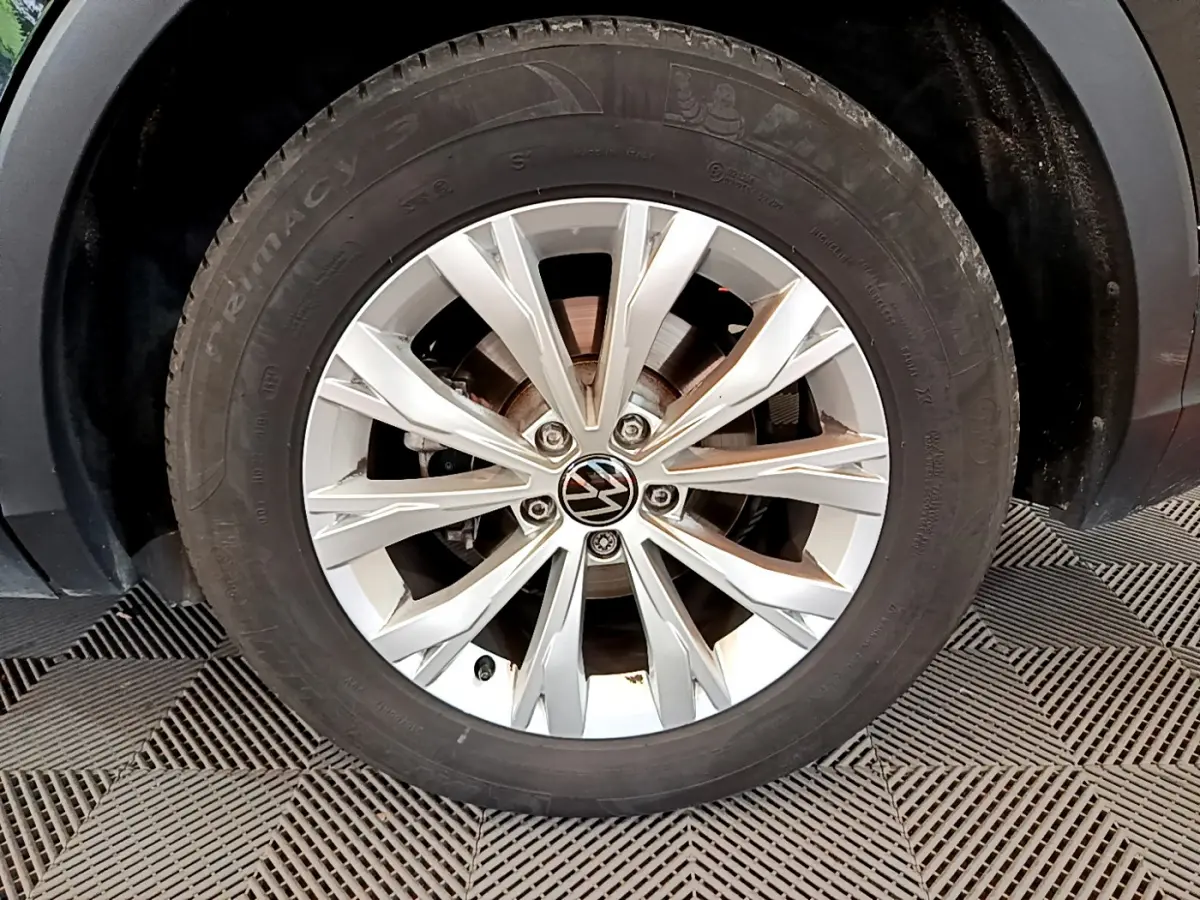 Gros plan sur la roue avant gauche du Volkswagen Tiguan noir, mettant en valeur la jante alliage argentée à 10 branches.