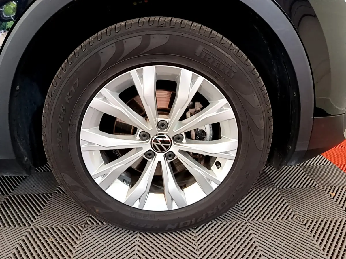 Gros plan sur la roue avant gauche du Volkswagen Tiguan noir 2021, jante alliage 17 pouces avec logo VW central.