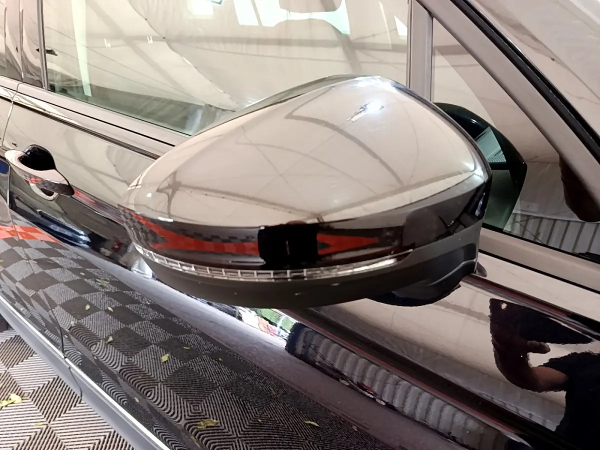 Gros plan sur le rétroviseur côté conducteur noir brillant du Volkswagen Tiguan 2.0 TDI 150 DSG7 Life Business.