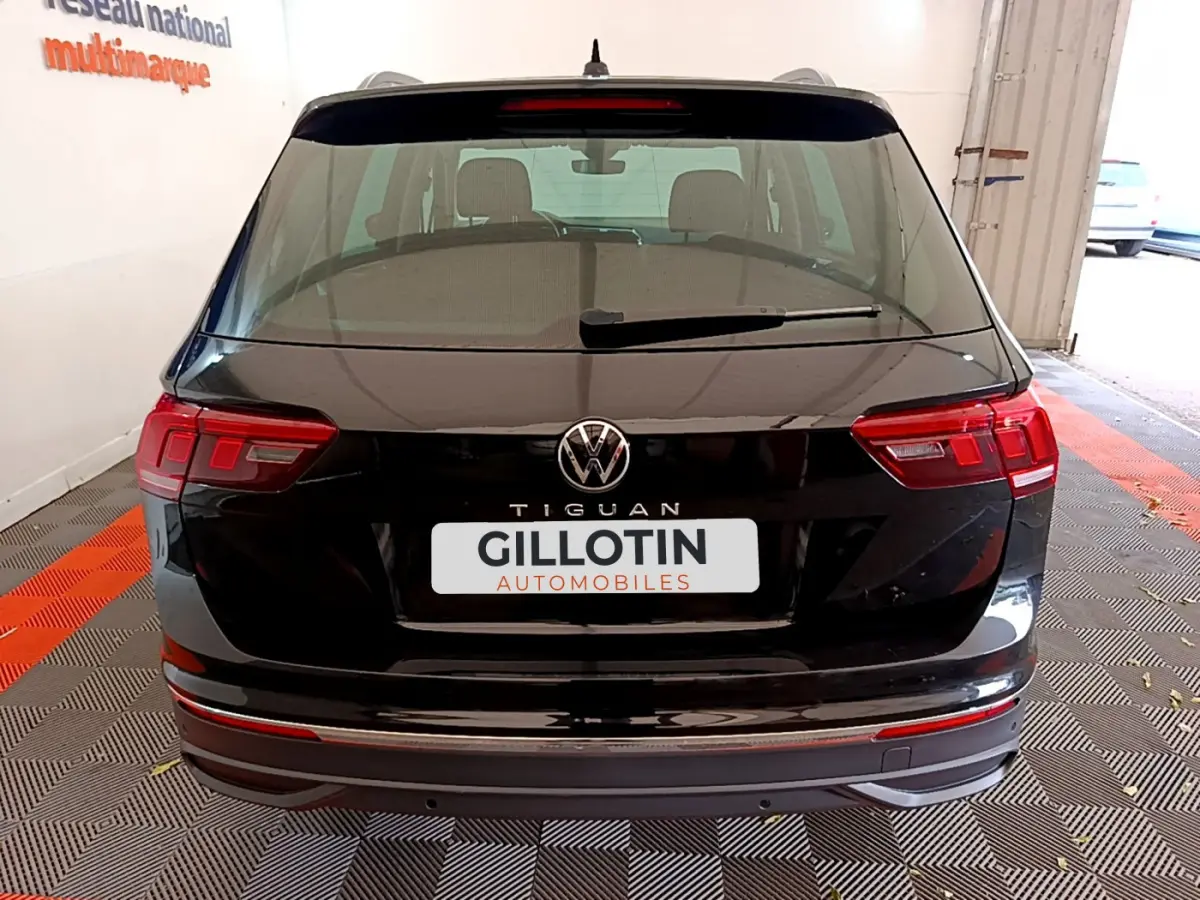 Vue arrière d'un Volkswagen Tiguan noir 2021 avec feux LED et logo central visible dans un garage.
