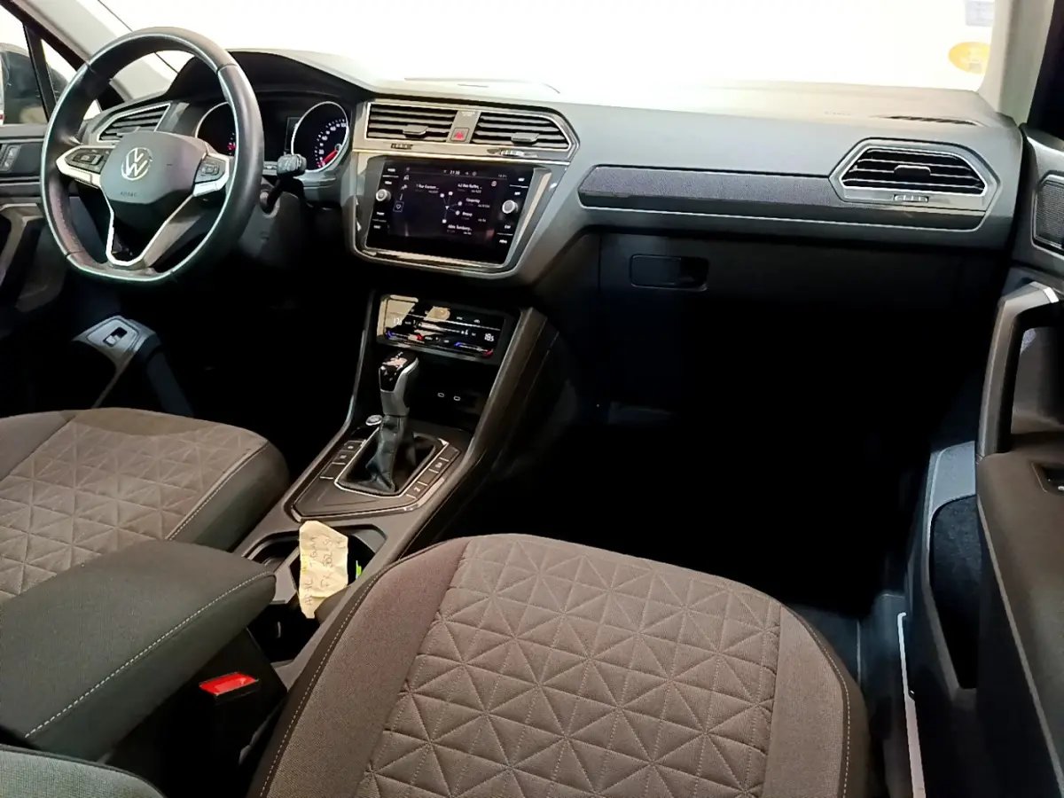 Intérieur avant du Volkswagen Tiguan 2.0 TDI 2021, vue du côté conducteur avec tableau de bord et console centrale noirs.