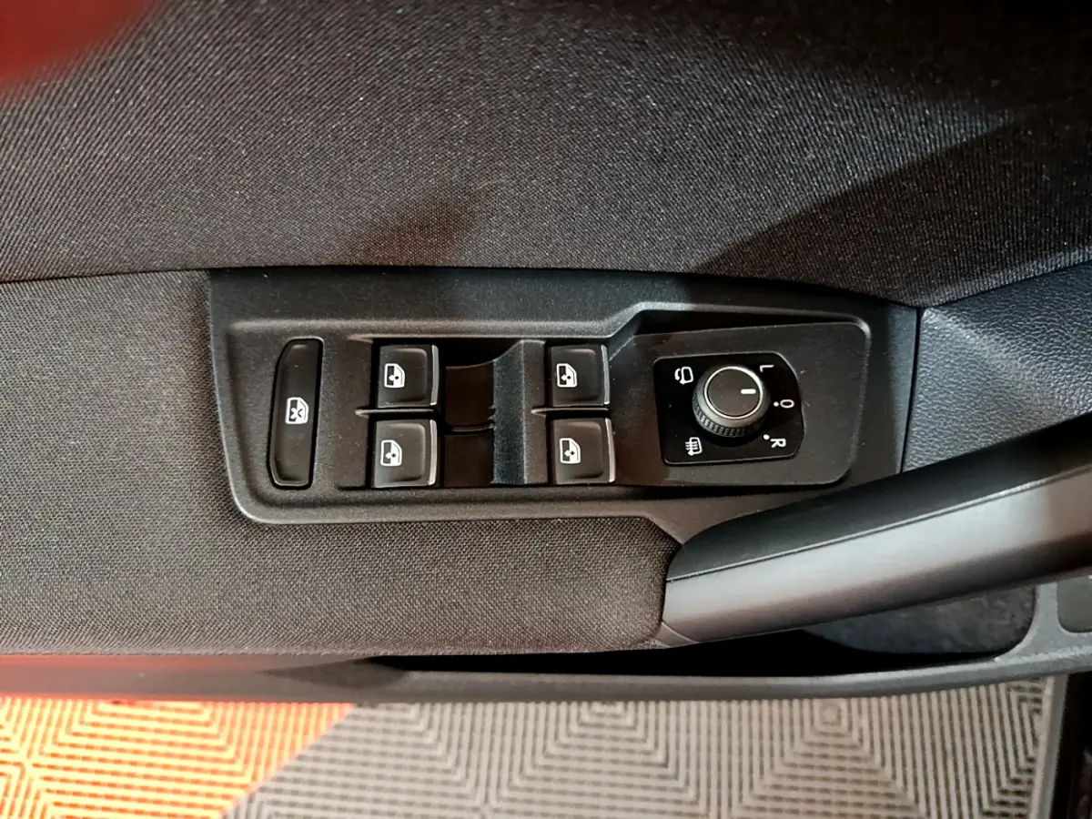 Vue rapprochée des commandes de lève-vitres et réglage des rétroviseurs côté conducteur du Volkswagen Tiguan noir.