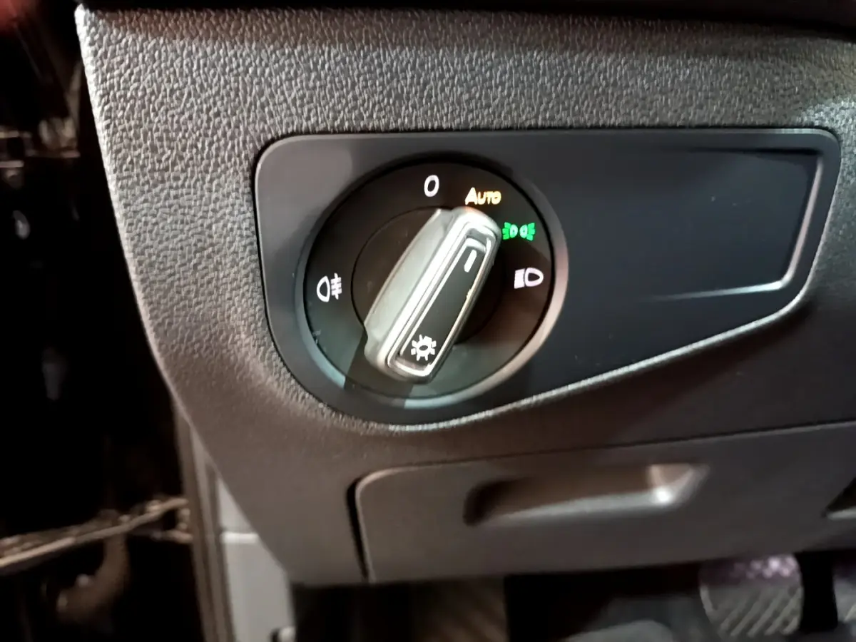Gros plan sur le bouton de commande des phares du Volkswagen Tiguan noir, avec réglage automatique activé.