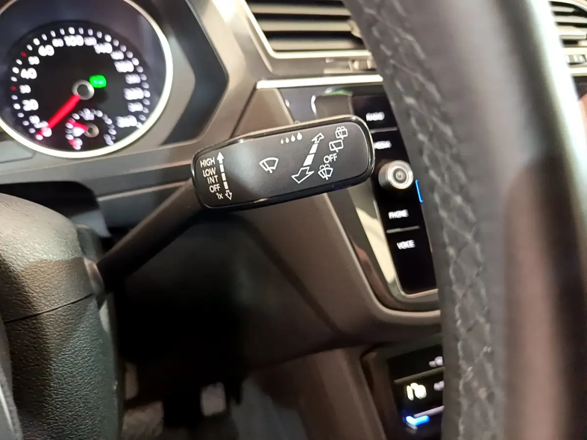 Gros plan sur le commodo d'essuie-glace à gauche du volant cuir dans l'habitacle noir du Volkswagen Tiguan 2021.