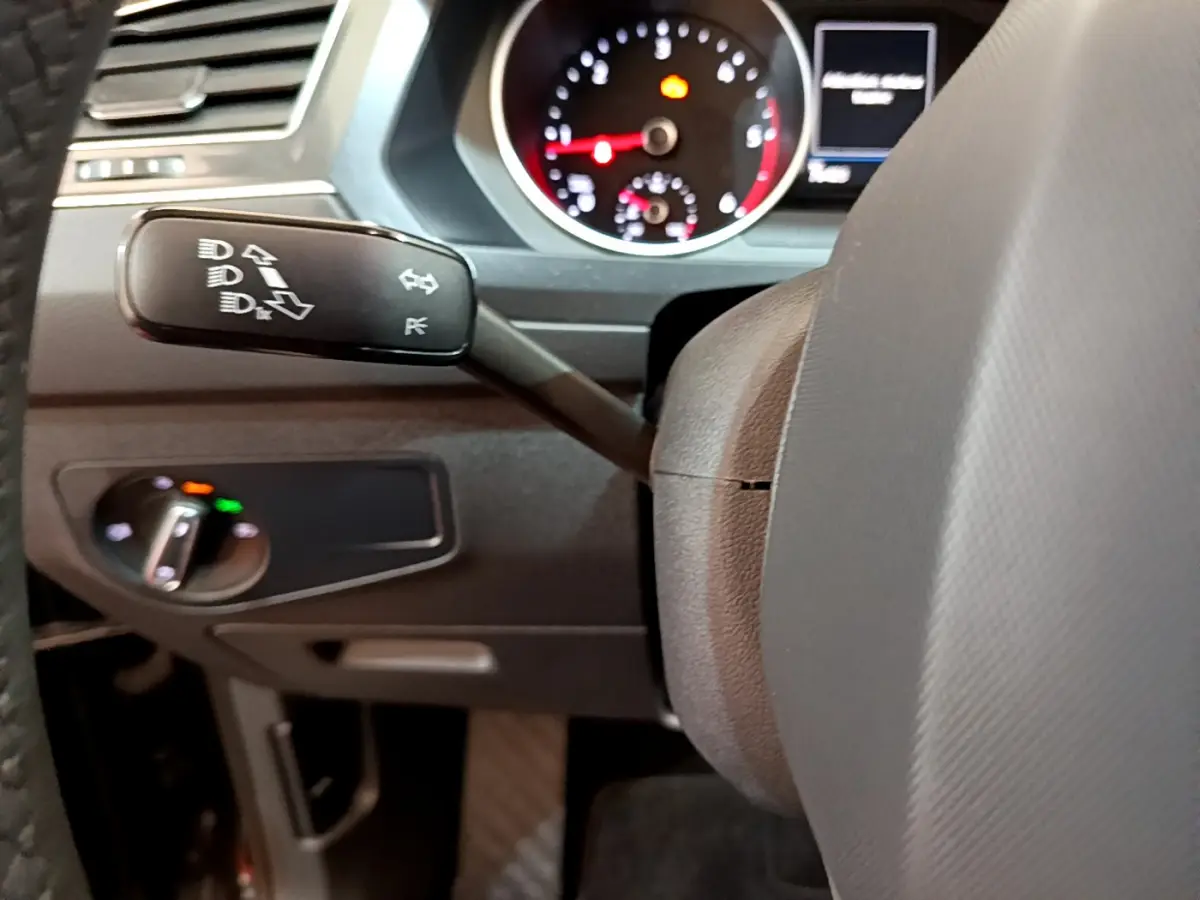 Gros plan sur le commodo gauche et le tableau de bord noir du Volkswagen Tiguan 2.0 TDI 2021 avec compteur analogique rouge et blanc.