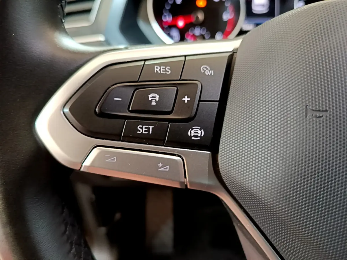 Gros plan sur les commandes multifonctions côté gauche du volant cuir du Volkswagen Tiguan noir 2021.