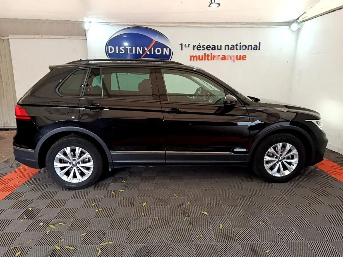 Vue latérale droite d'un Volkswagen Tiguan noir 2021 garé en intérieur avec jantes argentées et vitres teintées.