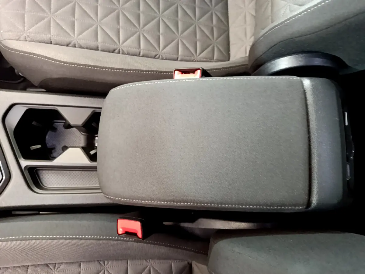 Vue rapprochée de l'accoudoir central noir et des sièges tissu gris du Volkswagen Tiguan 2021 intérieur.