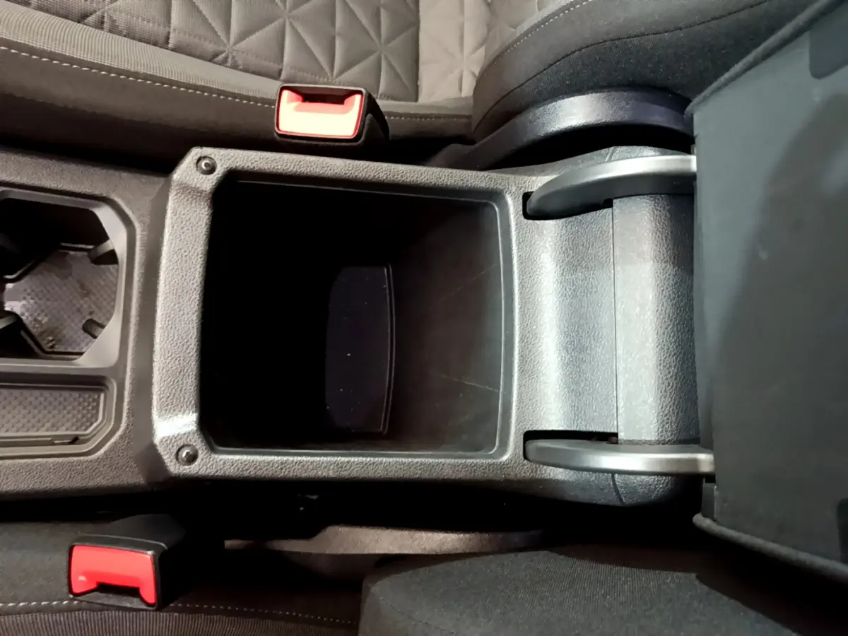 Vue plongeante sur la console centrale noire du Volkswagen Tiguan 2.0 TDI avec accoudoir ouvert et sièges gris à surpiqûres.