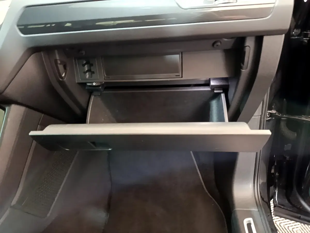 Gant de rangement ouvert côté passager dans l'habitacle noir du Volkswagen Tiguan 2021.