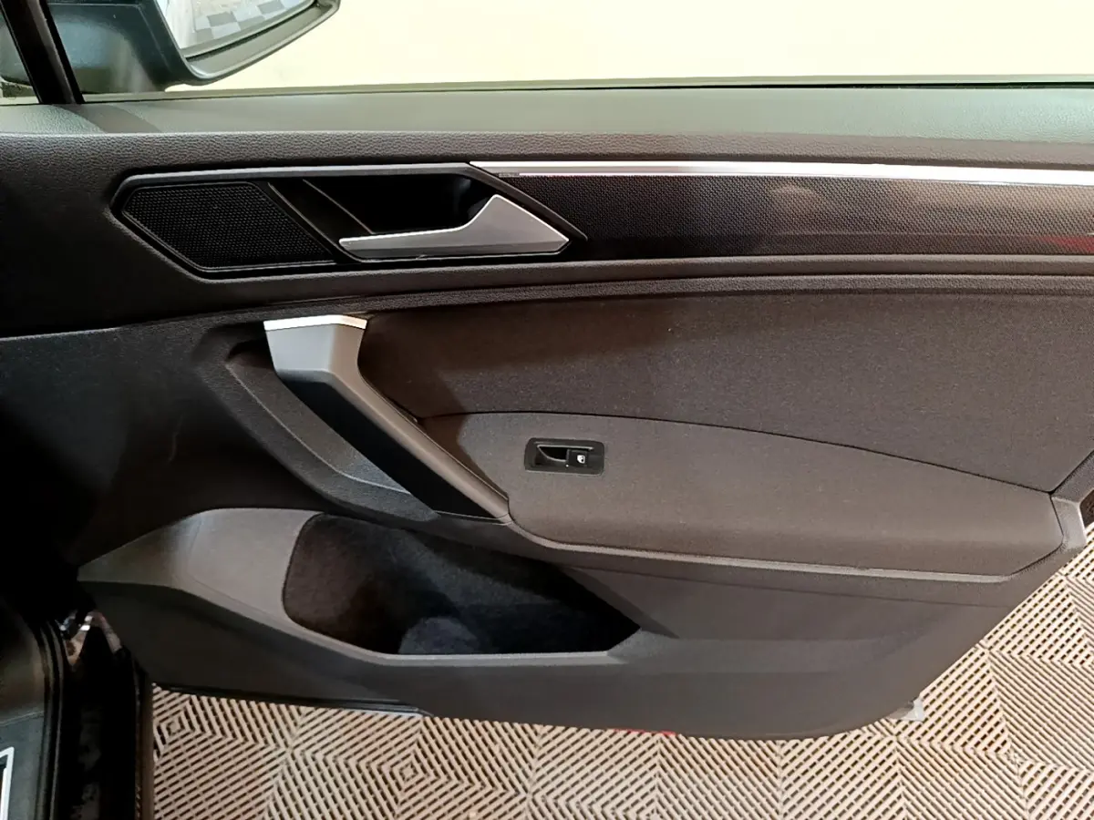 Gros plan sur la porte intérieure côté gauche noire du Volkswagen Tiguan 2021 avec poignée argentée et haut-parleur intégré.