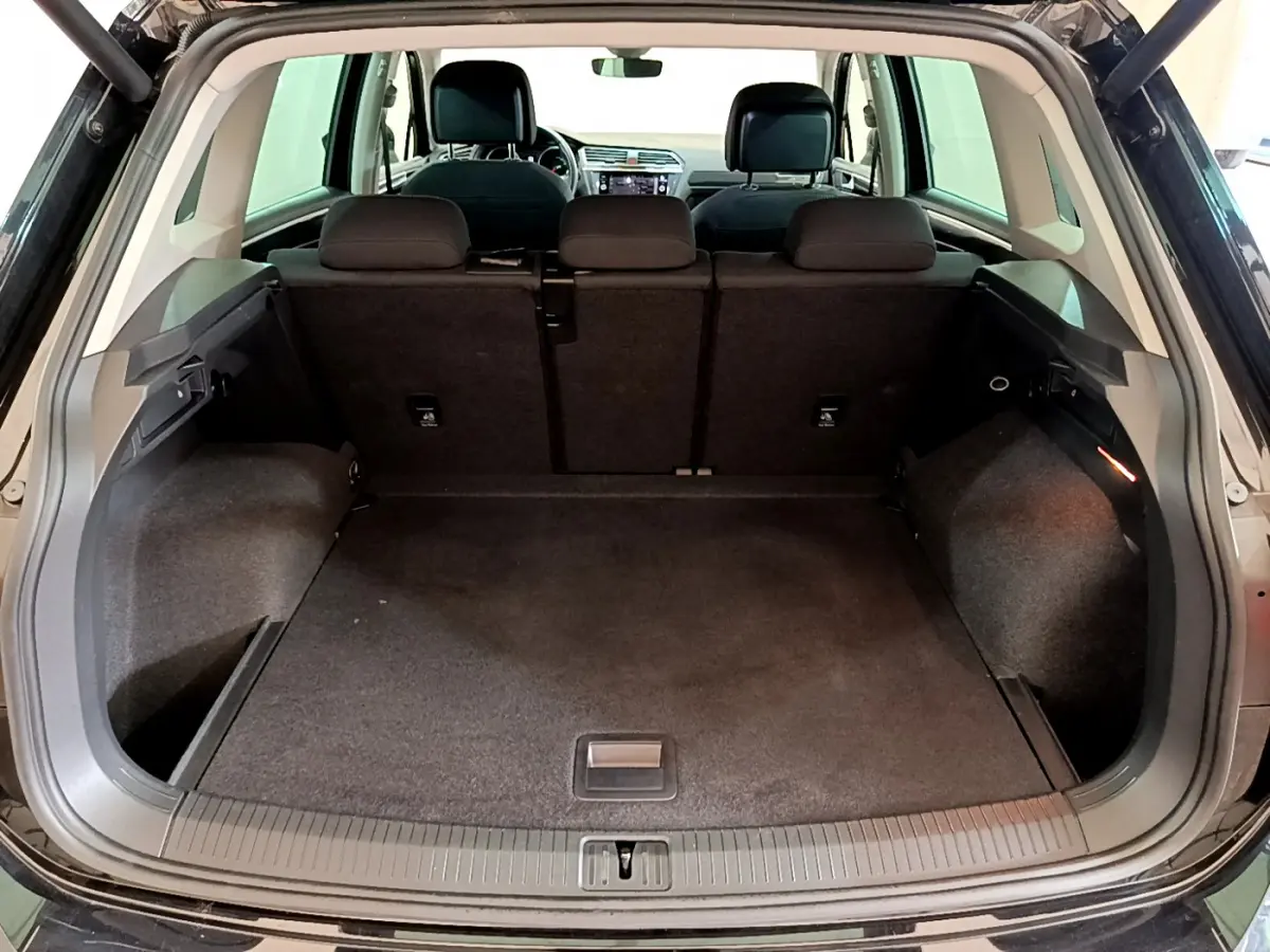 Coffre spacieux ouvert d'un Volkswagen Tiguan noir 2021, vue arrière avec banquette arrière en tissu noir.