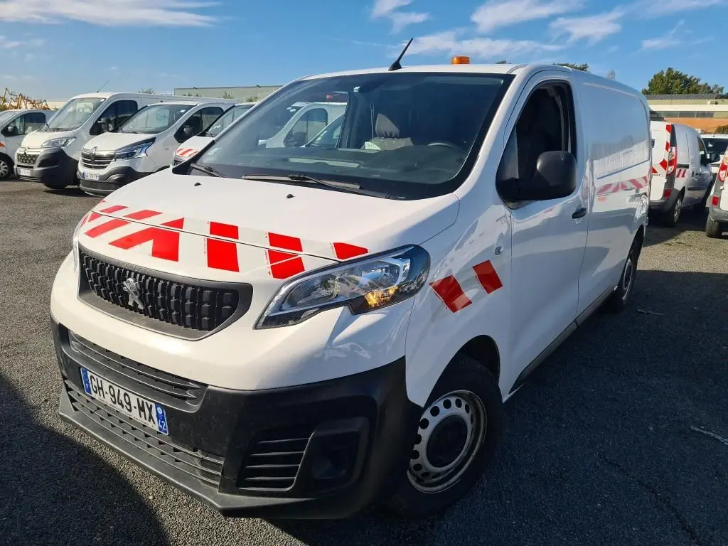 Vue 3/4 avant droit d'un Peugeot Expert Fourgon blanc 2022 avec bandes rouges et gyrophare orange sur le toit.