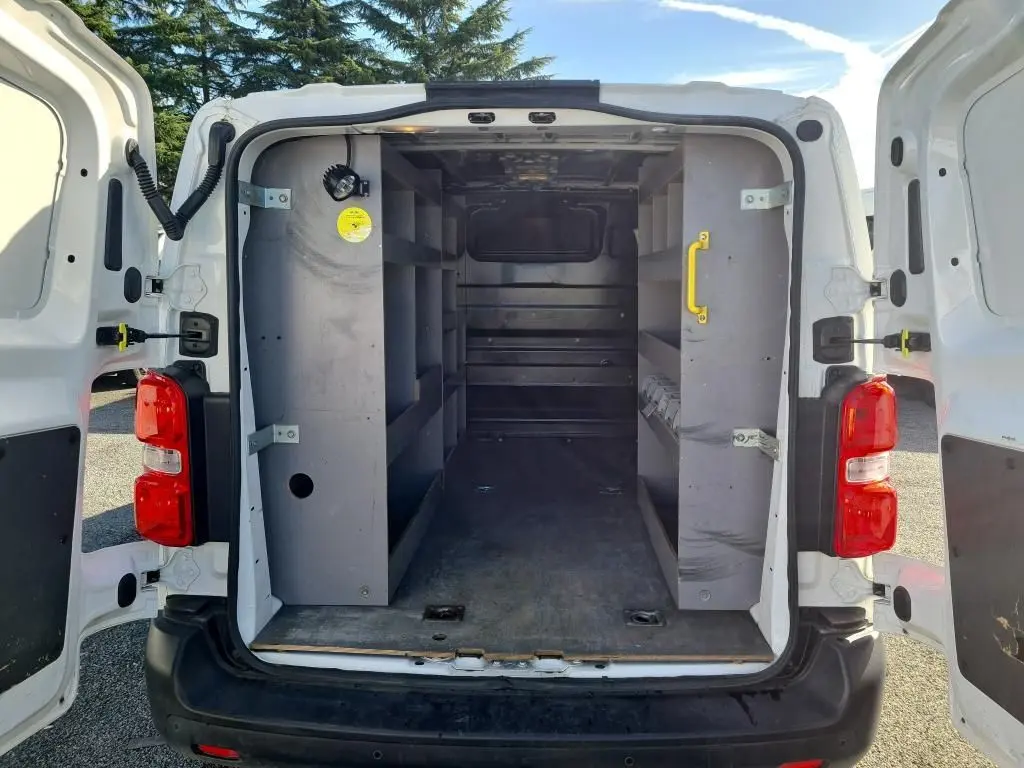 Vue arrière du Peugeot Expert Fourgon blanc 2022 avec portes ouvertes montrant l'intérieur équipé de rangements gris.