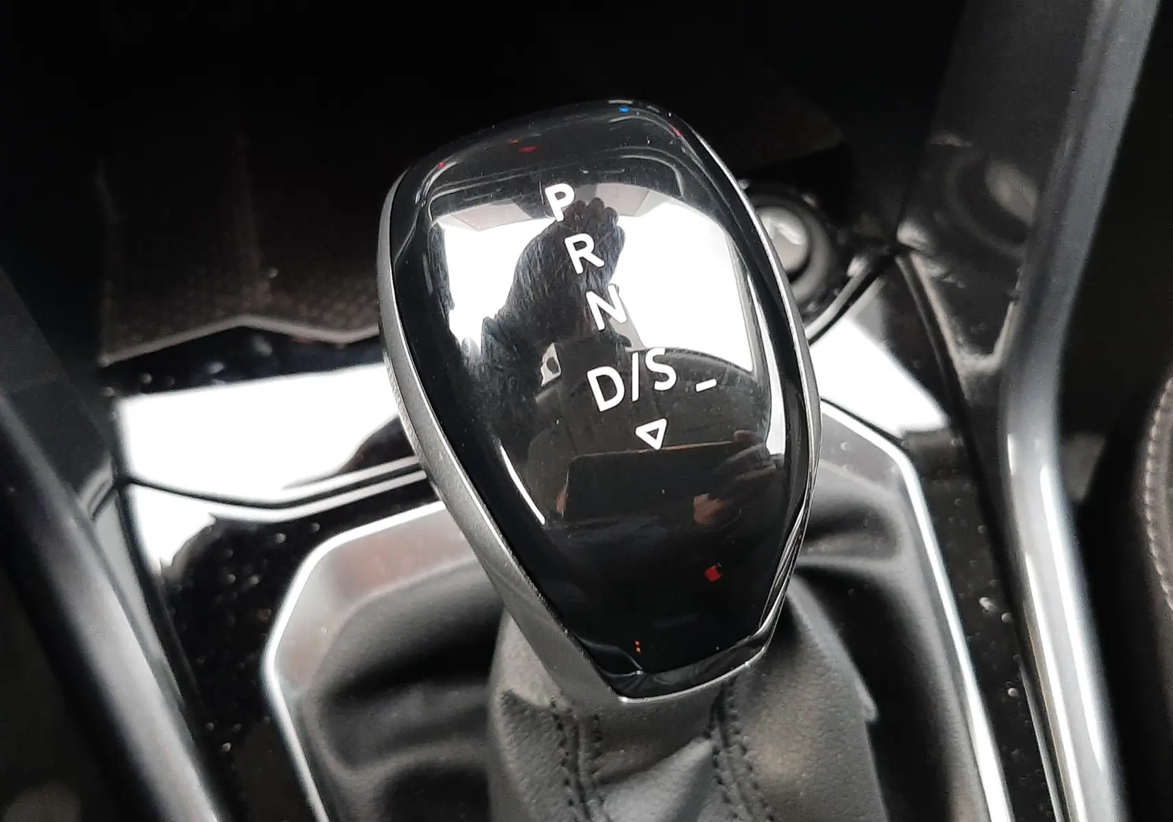 Gros plan sur la console centrale noire du Volkswagen T-Roc 2023 avec porte-gobelets et boutons de frein à main électronique.