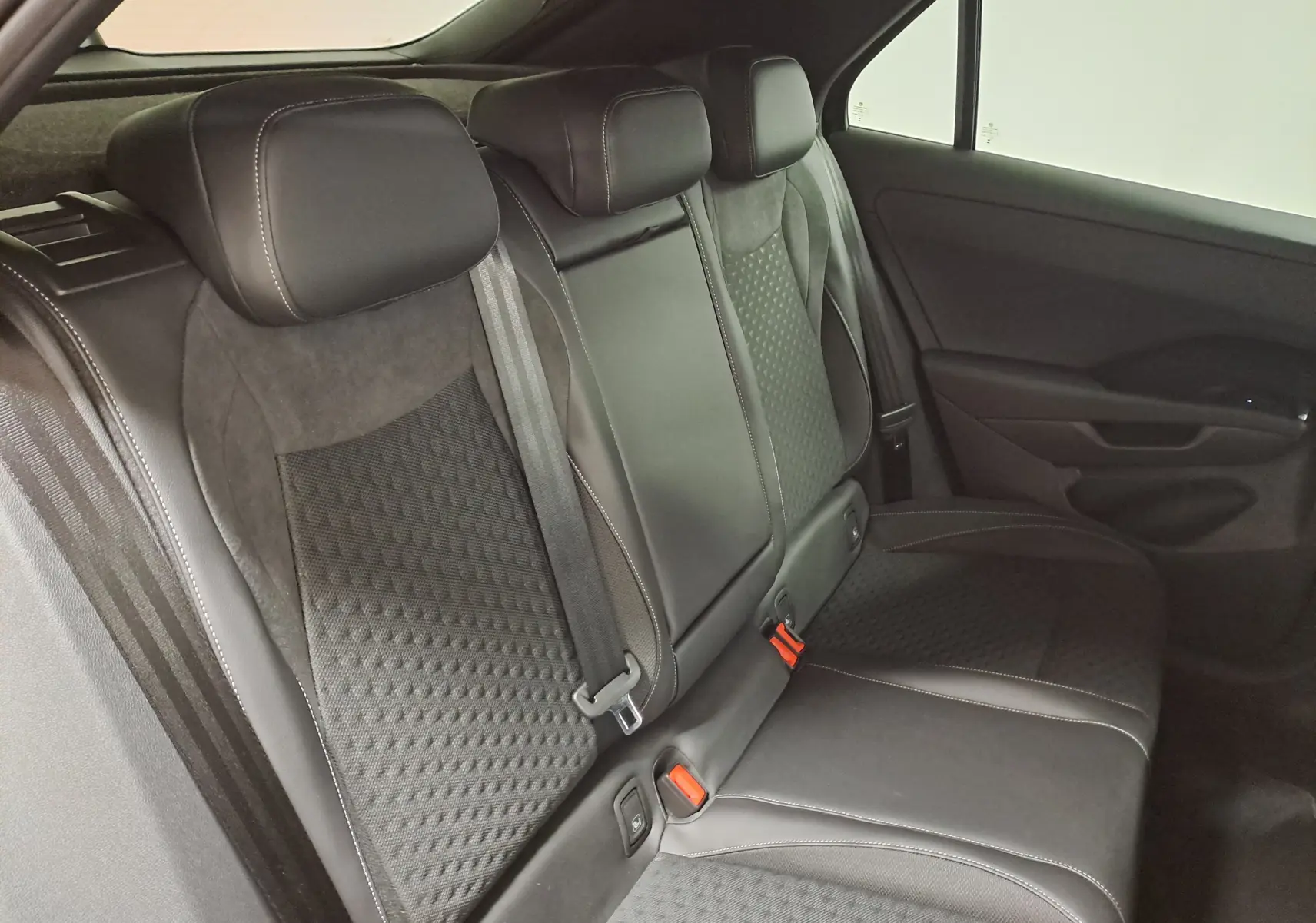 Vue intérieure du siège arrière droit du Volkswagen T-Roc 2026 noir, avec sellerie mixte tissu et cuir et appuie-têtes intégrés.