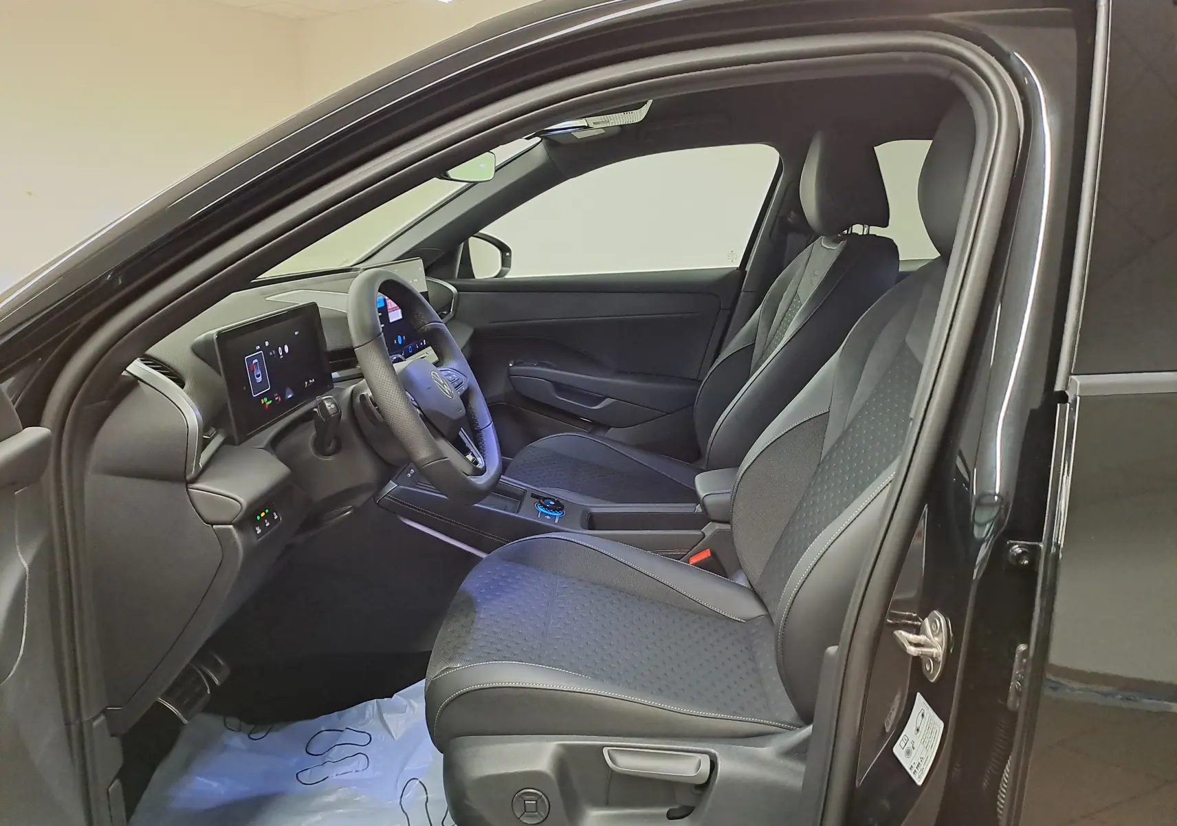 Vue intérieure côté conducteur du Volkswagen T-Roc noir ébène 2026, sièges en tissu et tableau de bord digital.