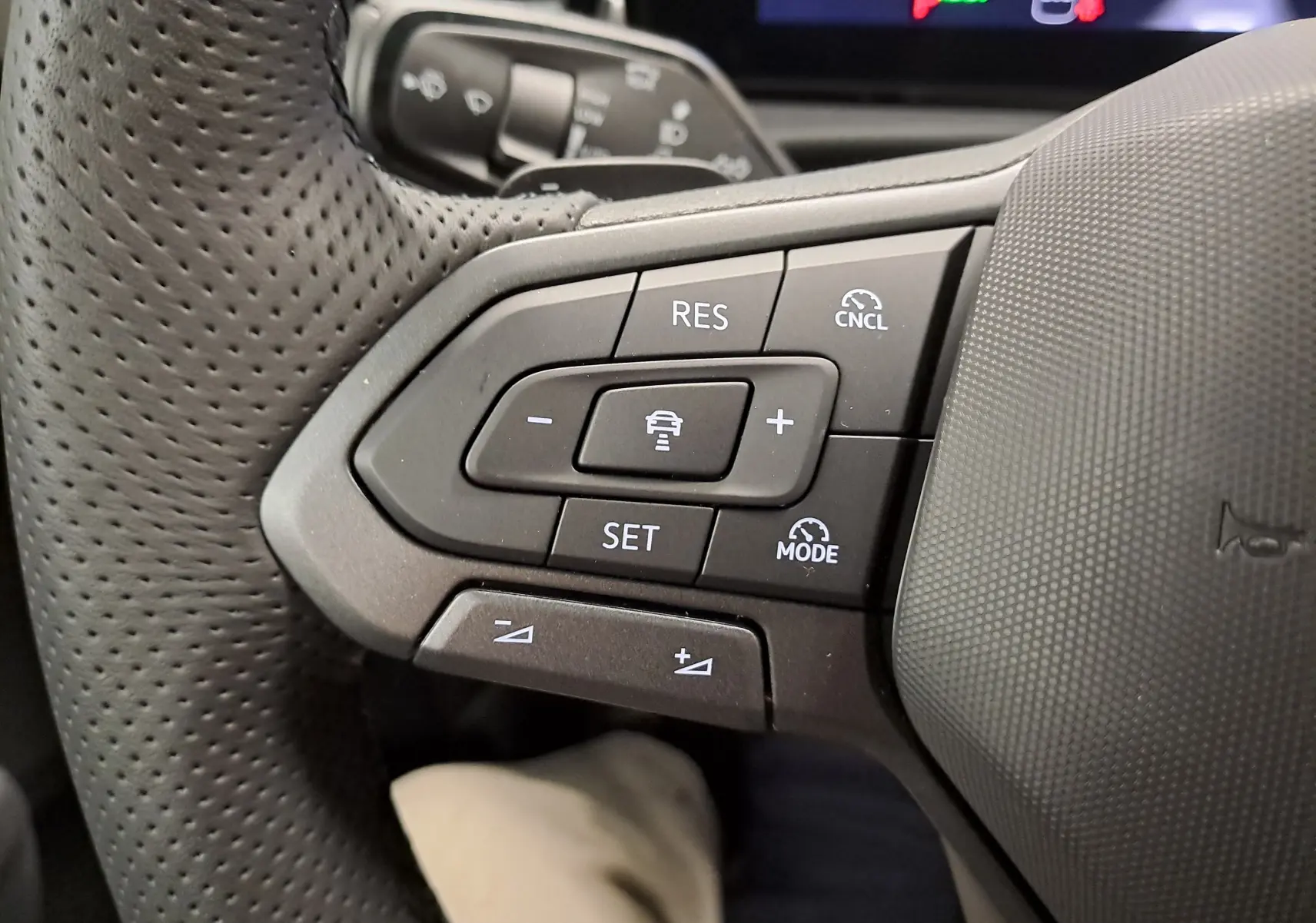 Gros plan sur les commandes au volant côté gauche du Volkswagen T-Roc noir Ébène, version R-Line 2026.