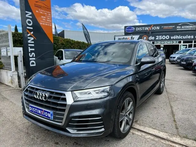 Audi Q5 gris foncé en 3/4 avant droit, finition S Line avec calandre distinctive et jantes alliage visibles.