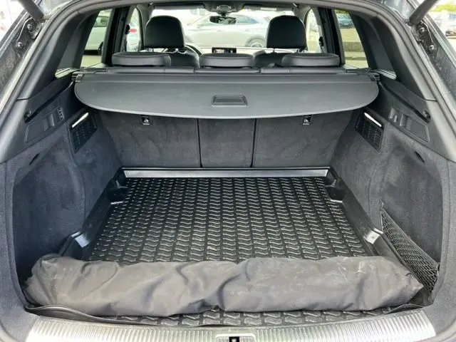 Coffre ouvert d'un Audi Q5 gris foncé 2018, vue arrière montrant la protection de chargement et la plage arrière.