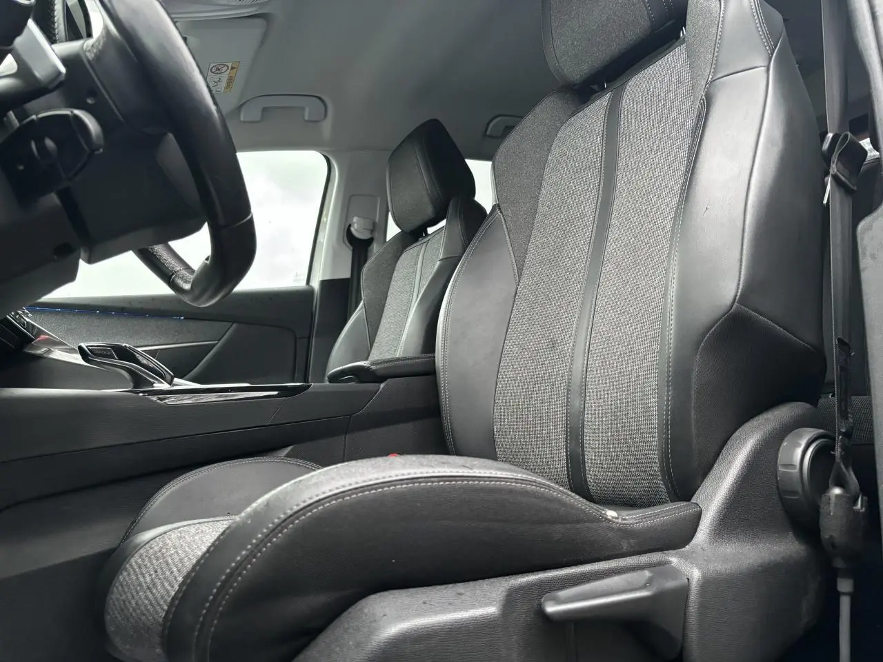 Vue intérieure côté conducteur du Peugeot 3008 2018 montrant les sièges en tissu et cuir noir avec détails gris.