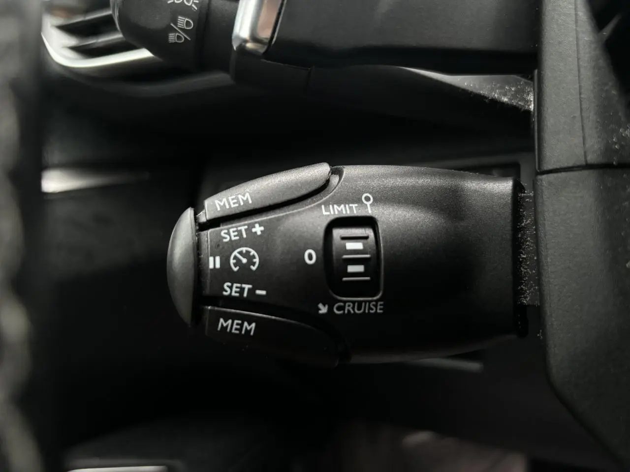 Commande de régulateur de vitesse noir vue en gros plan à gauche du volant d'un Peugeot 3008 blanc de 2018
