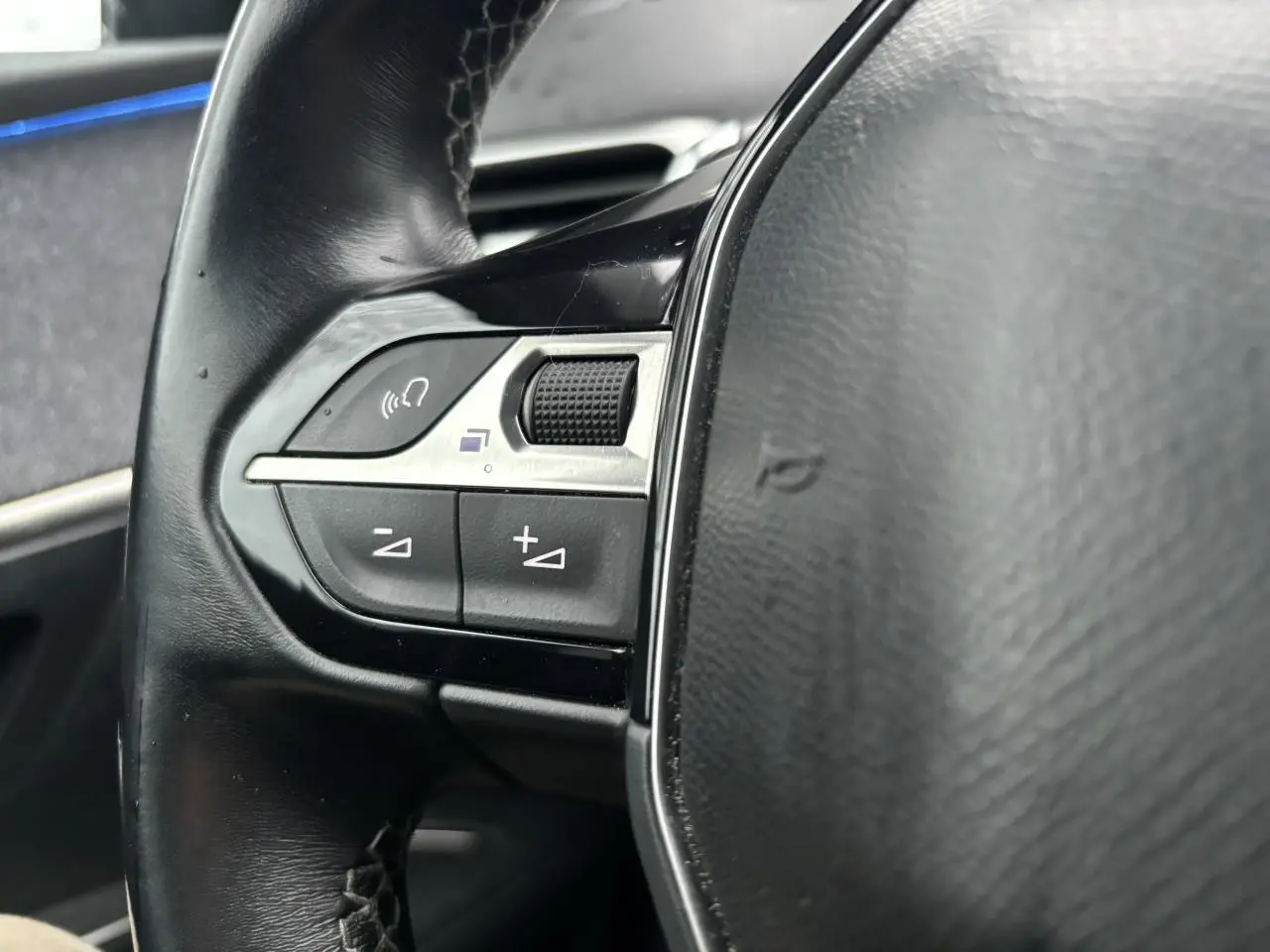 Gros plan sur les commandes gauche du volant noir du Peugeot 3008 blanc nacré de 2018.