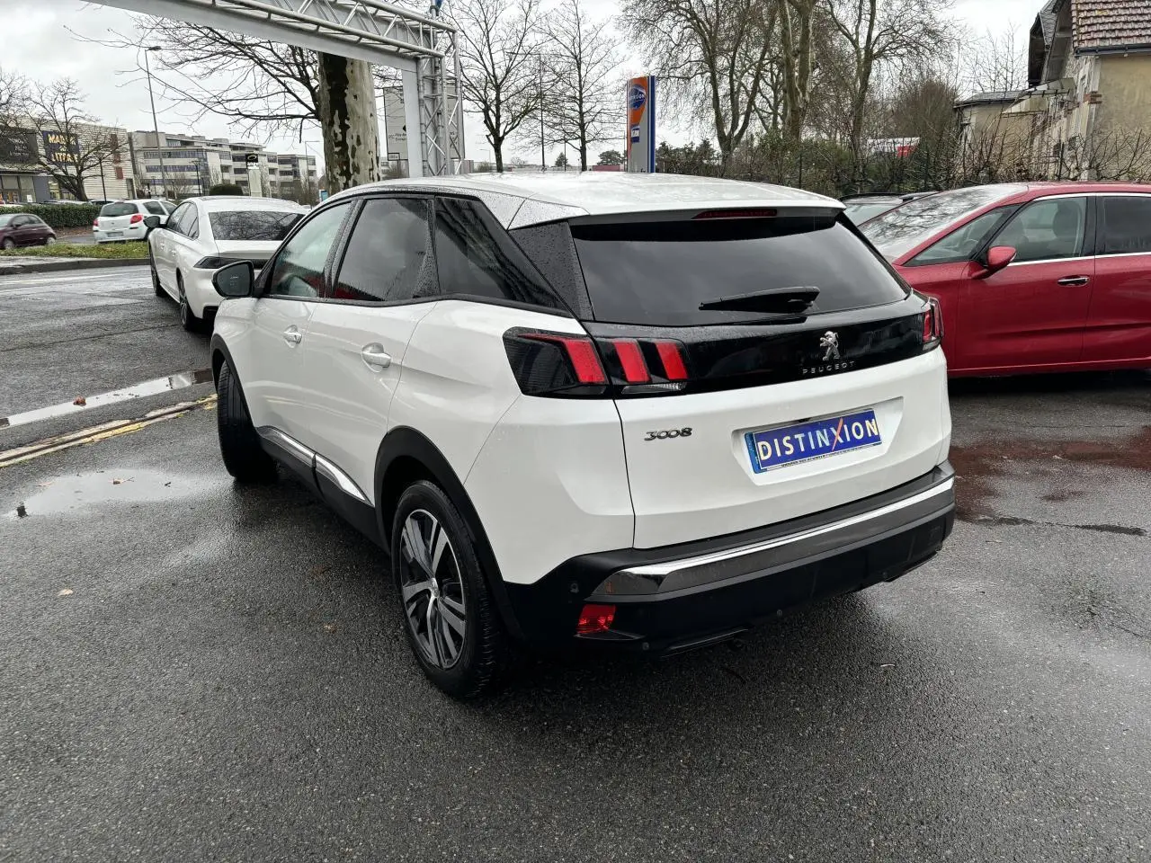 Vue 3/4 arrière droite d'un Peugeot 3008 blanc nacré avec feux arrière à griffes et toit noir.