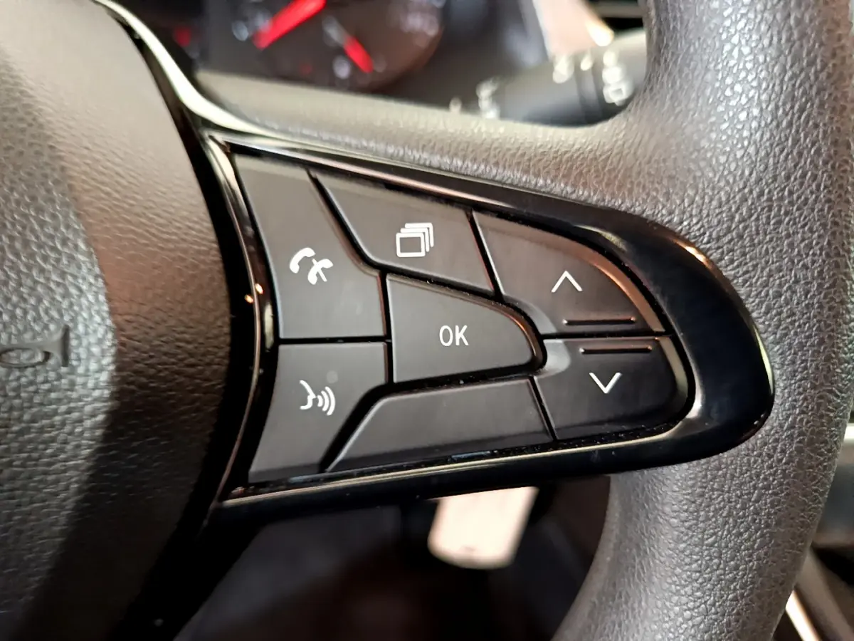 Gros plan sur les commandes multifonctions noires du volant du Renault Kangoo bleu 2023, version Equilibre TCe 100.