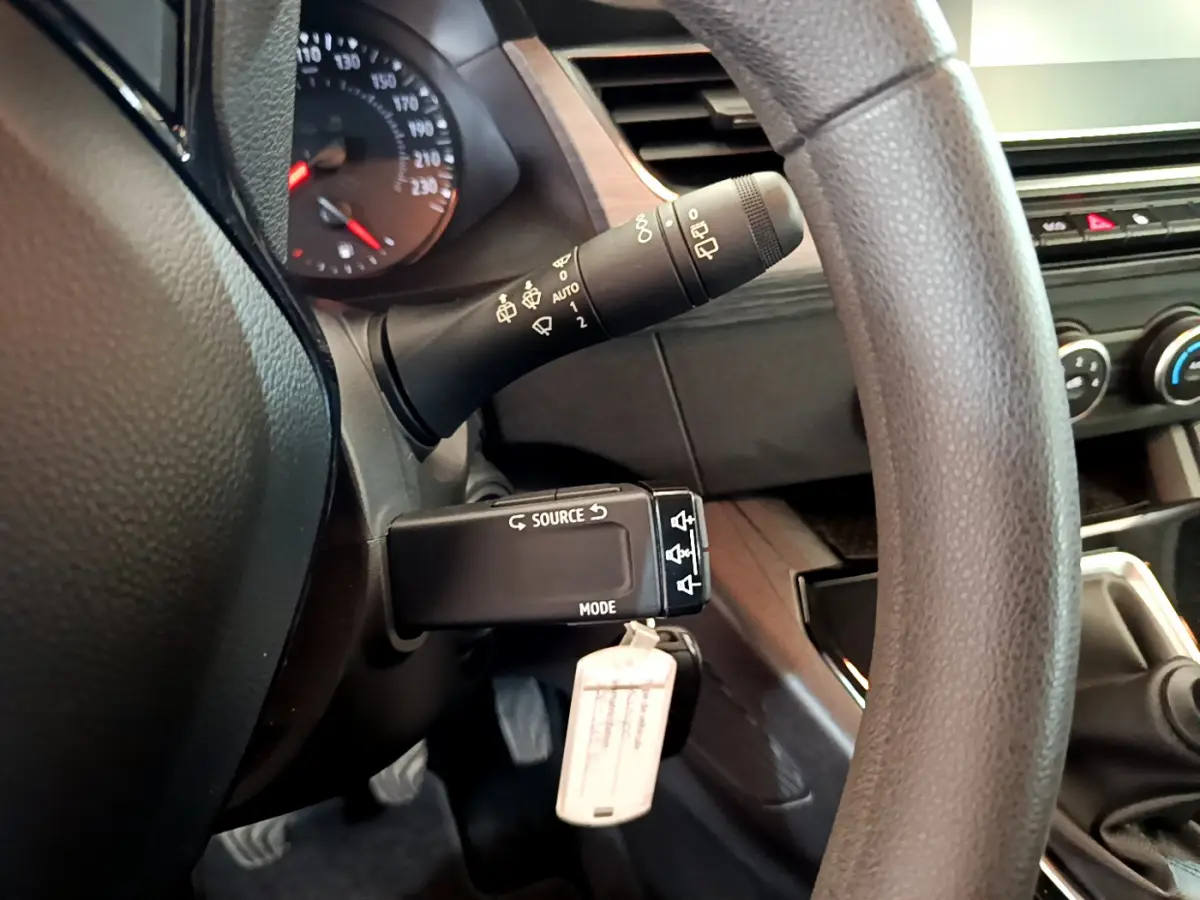 Gros plan sur la commande multifonction et partie du volant du Renault Kangoo bleu 2023, intérieur noir.