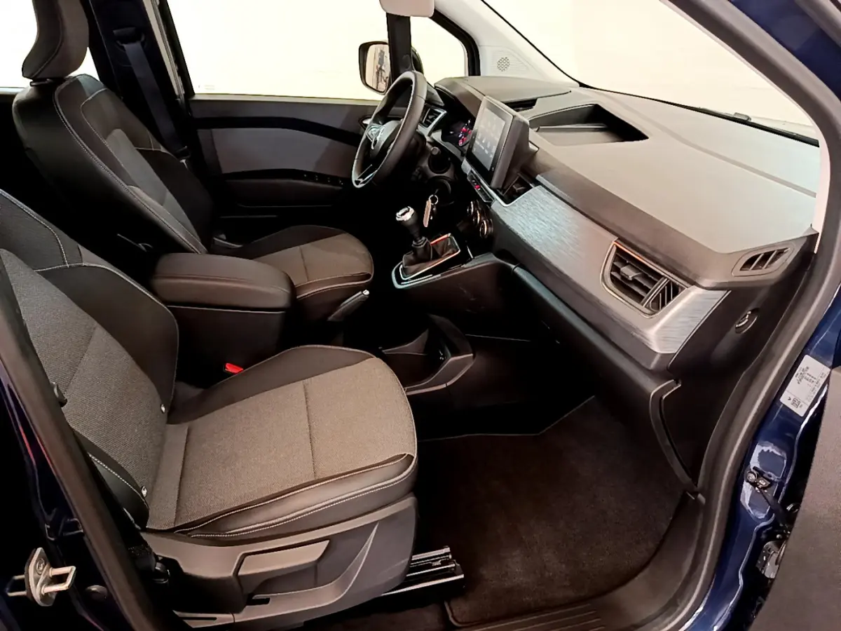 Intérieur avant droit du Renault Kangoo bleu 2023, sièges tissu gris, tableau de bord moderne avec écran tactile central.