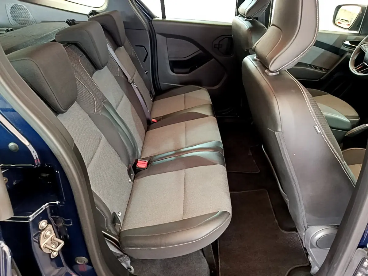 Vue intérieure côté gauche sur la banquette arrière grise et noire du Renault Kangoo Bleu 2023, avec sièges rabattables.