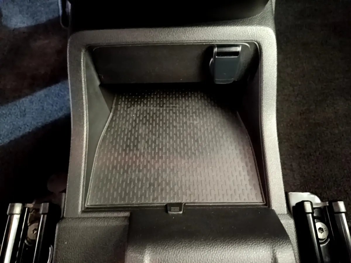 Gros plan sur le rangement central noir du Renault Kangoo bleu 2023, version Equilibre TCe 100, intérieur sobre et fonctionnel.