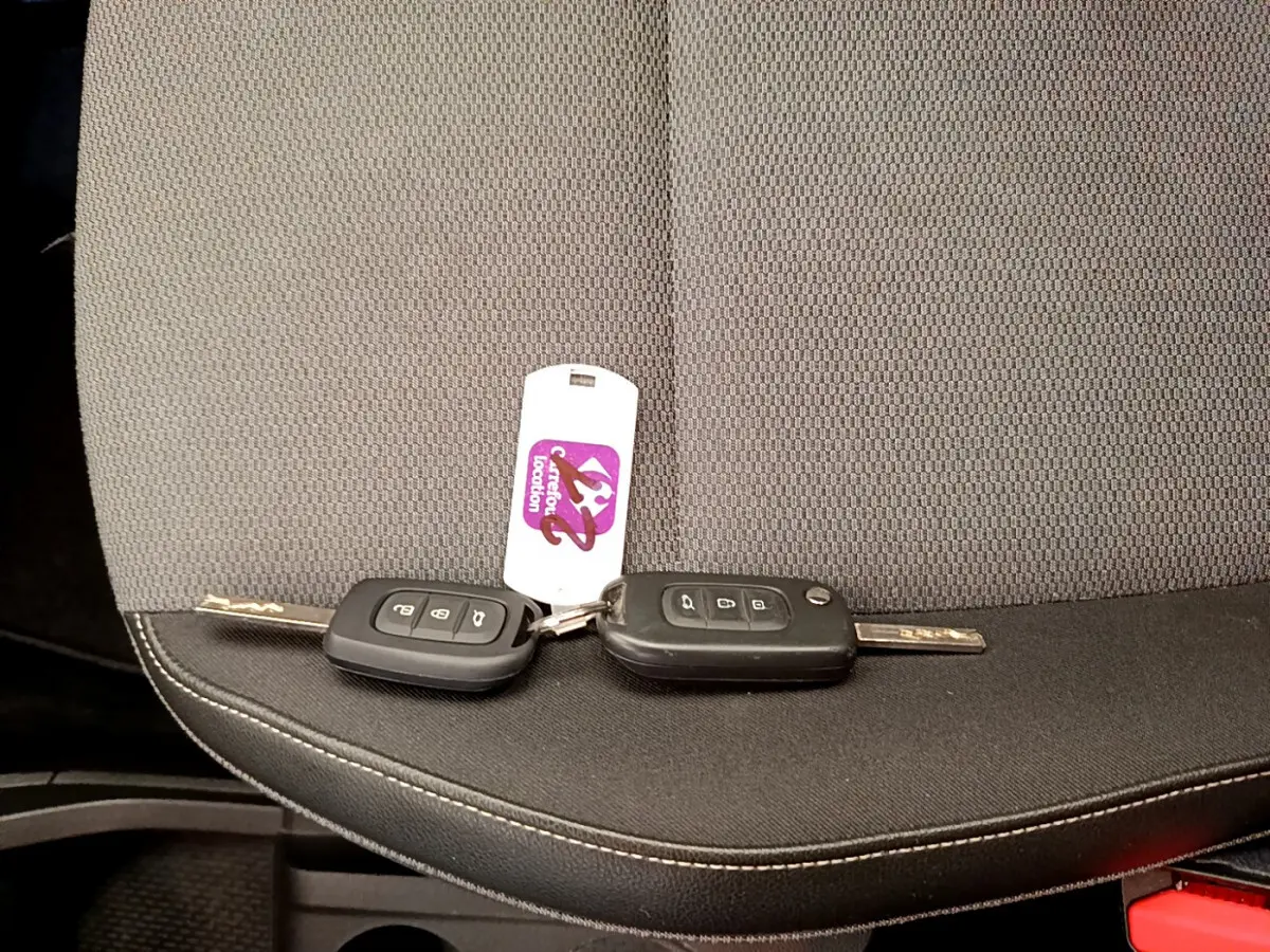 Gros plan sur deux clés Renault noires posées sur un siège tissu gris foncé à coutures blanches.