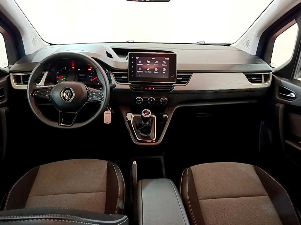 Vue intérieure avant du Renault Kangoo 2023, tableau de bord moderne avec écran tactile central et volant multifonctions.