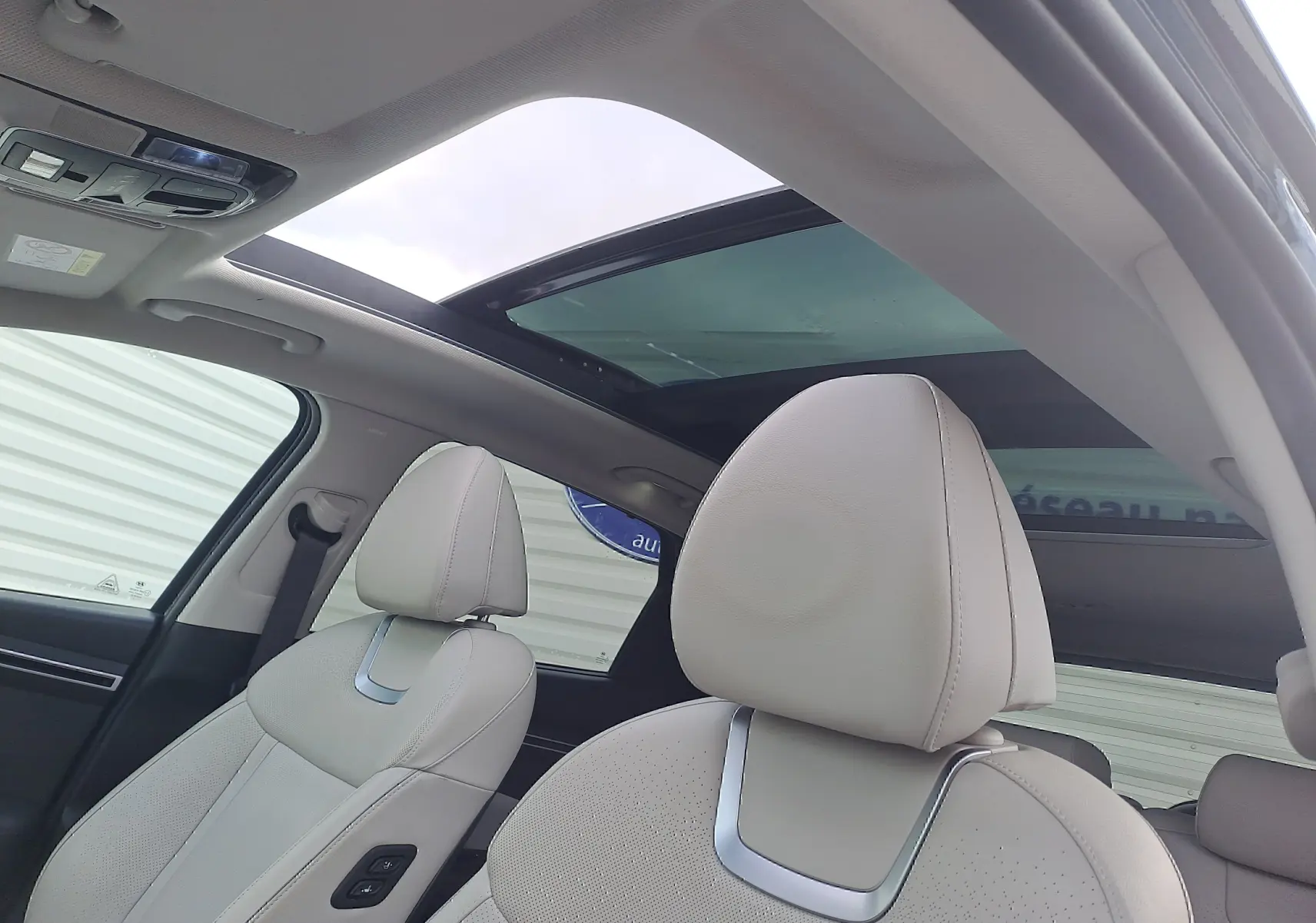 Intérieur beige du Hyundai Tucson 2023 avec toit panoramique en verre, vue sur les sièges avant côté gauche.