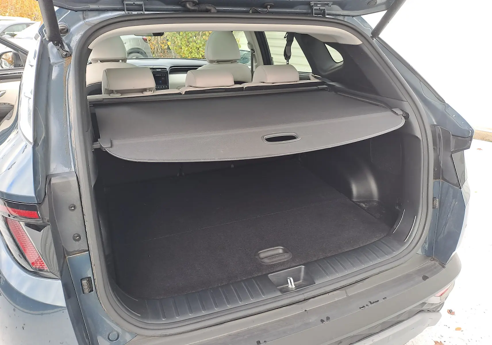 Coffre ouvert en vue arrière d'un Hyundai Tucson Cypress Green 2023 avec cache-bagages et intérieur beige visible.