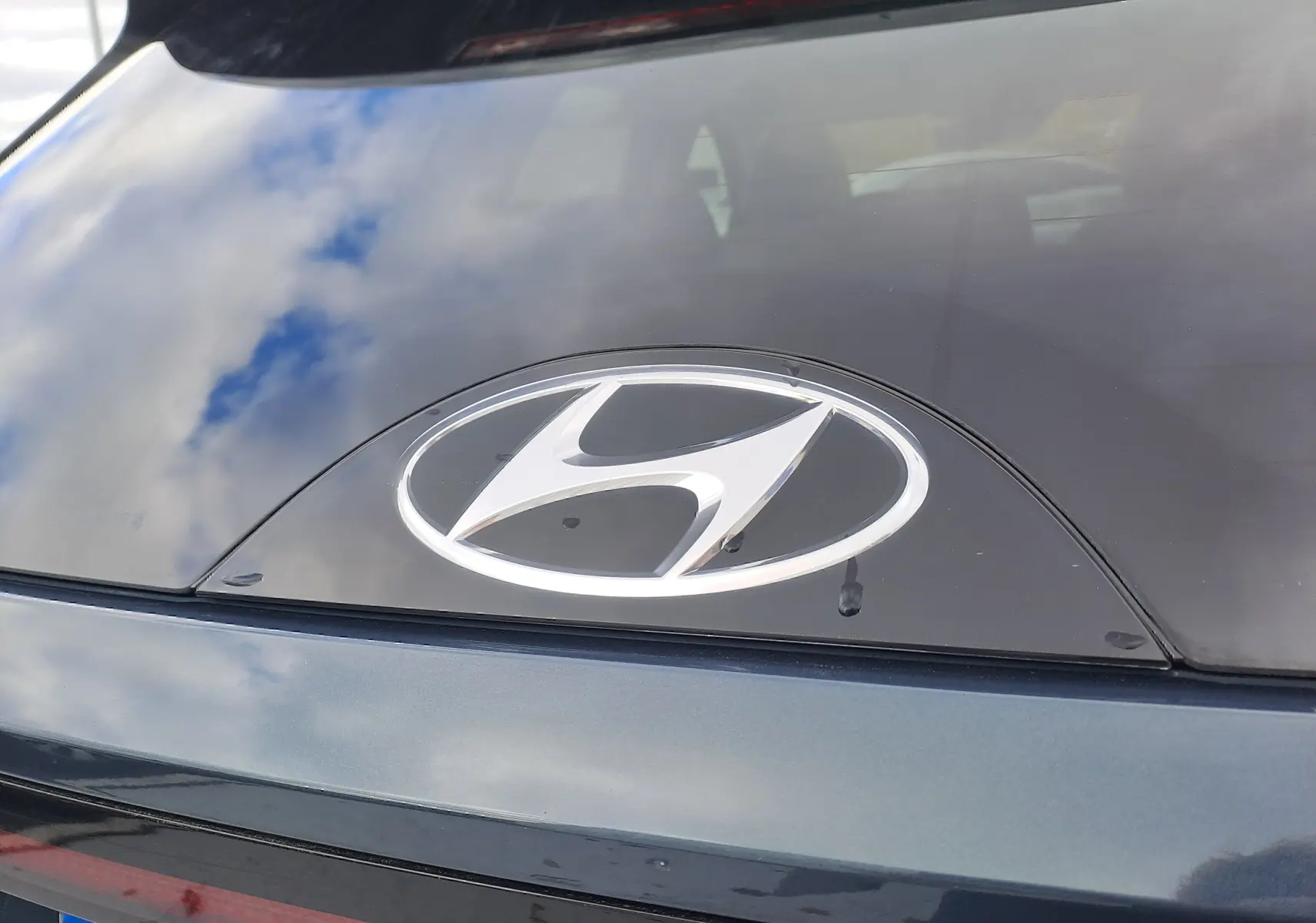 Gros plan sur l'arrière d'un Hyundai Tucson Cypress Green 2023, mettant en valeur le logo Hyundai chromé sur vitre noire.