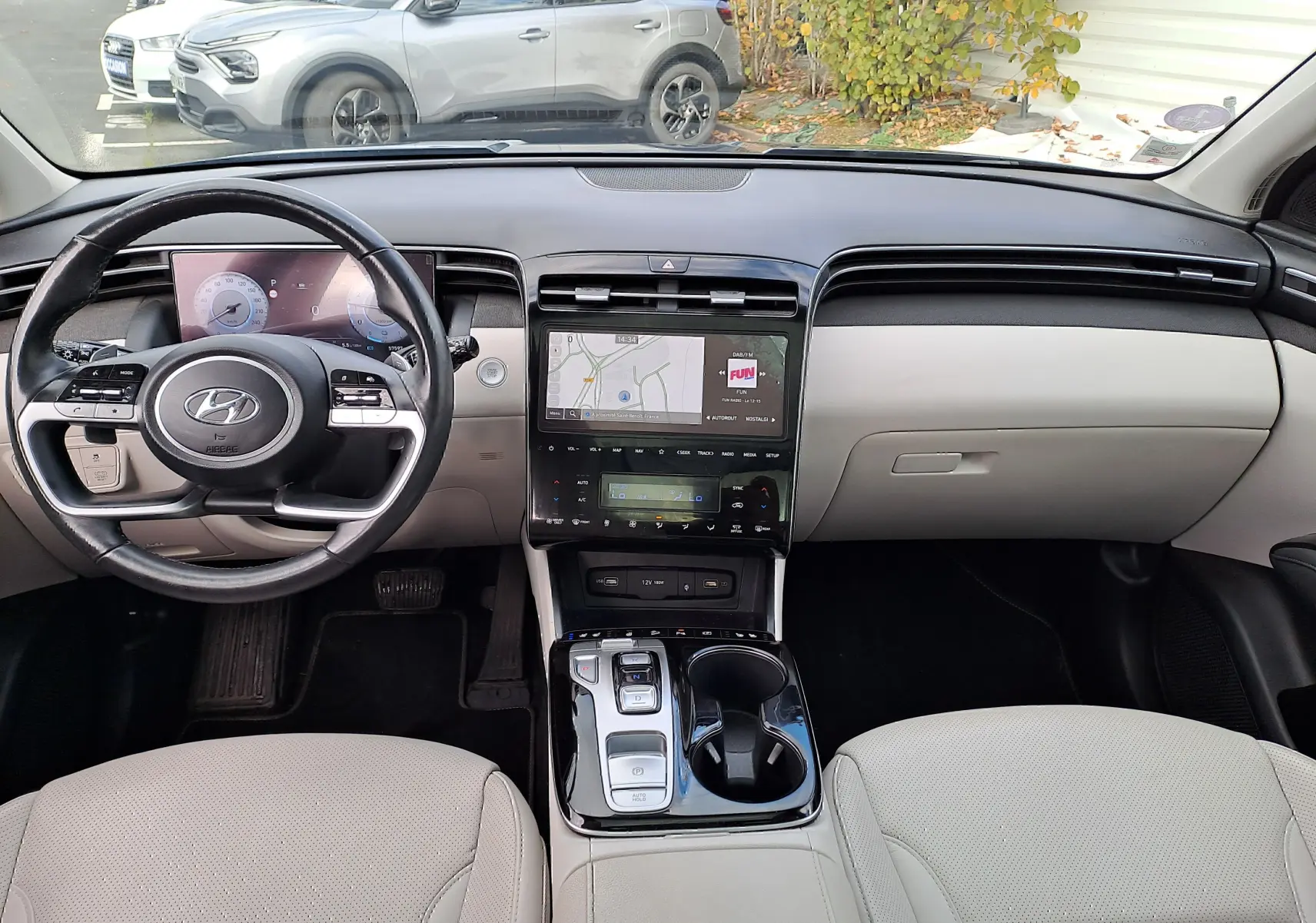 Vue intérieure du tableau de bord et console centrale du Hyundai Tucson 2023 avec sellerie beige et écran tactile affichant la navigation.