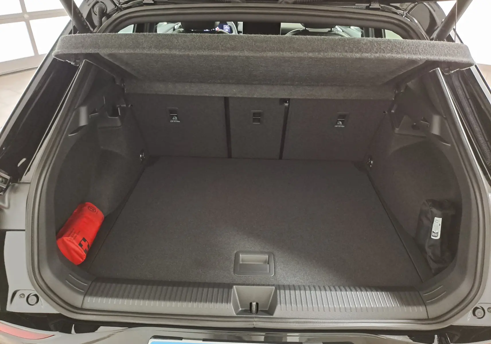 Coffre ouvert du Volkswagen T-Roc 2026 noir ébène, vue arrière montrant l'espace de chargement et les rangements latéraux.