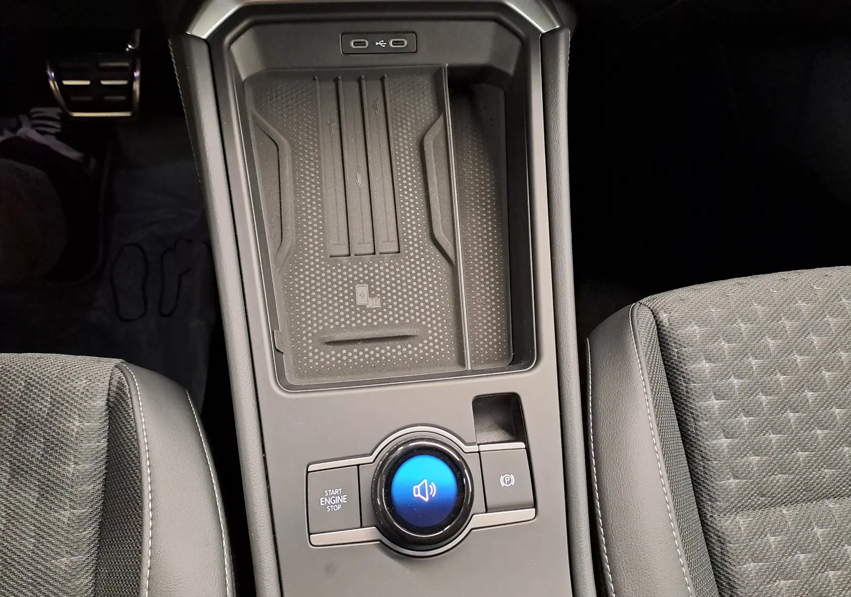 Vue rapprochée de la console centrale du Volkswagen T-Roc 2026, avec bouton start/stop et chargeur sans fil.