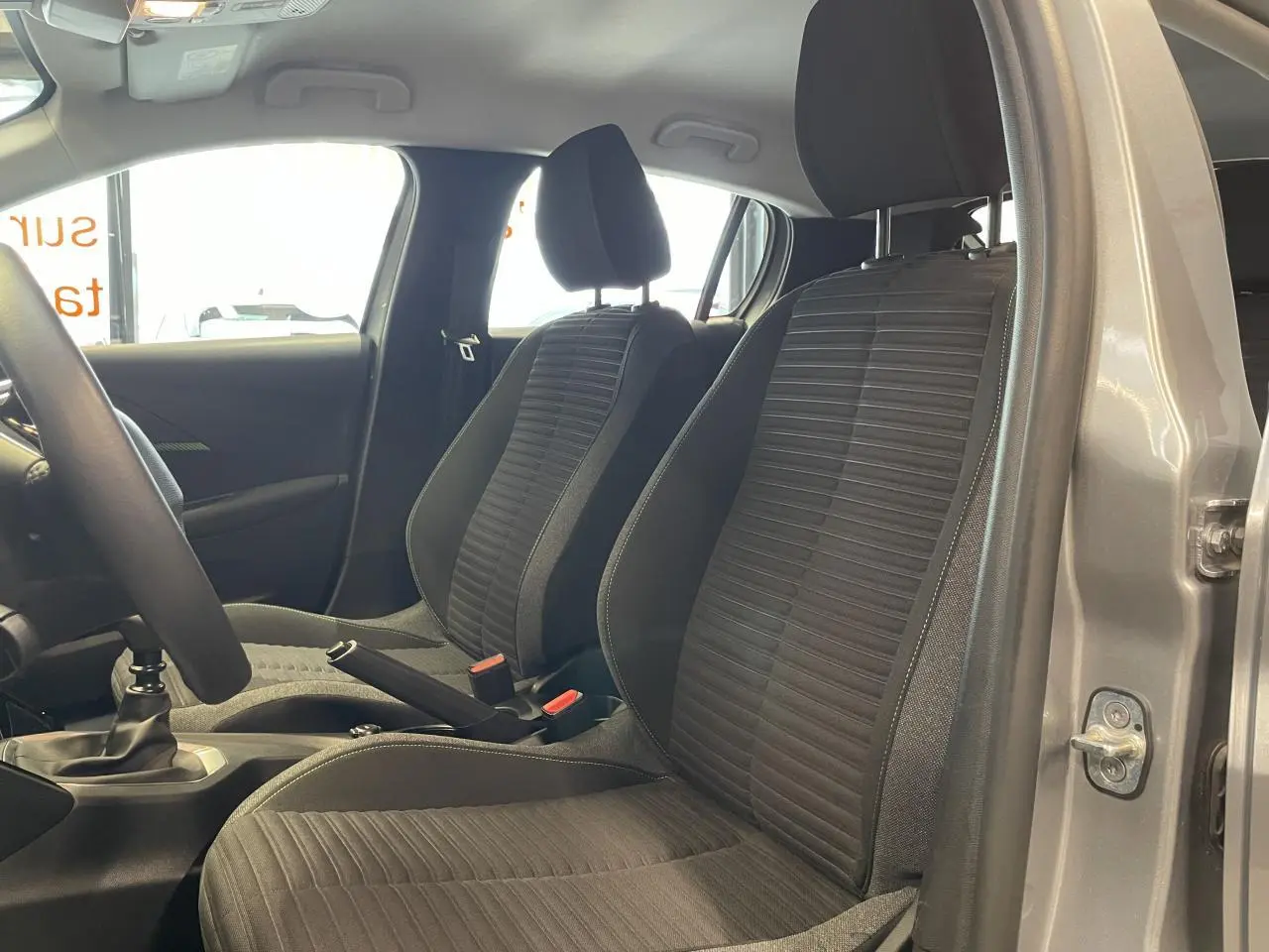 Vue intérieure côté gauche sur les sièges avant tissu noir de la Peugeot 208 gris clair avec boîte manuelle.