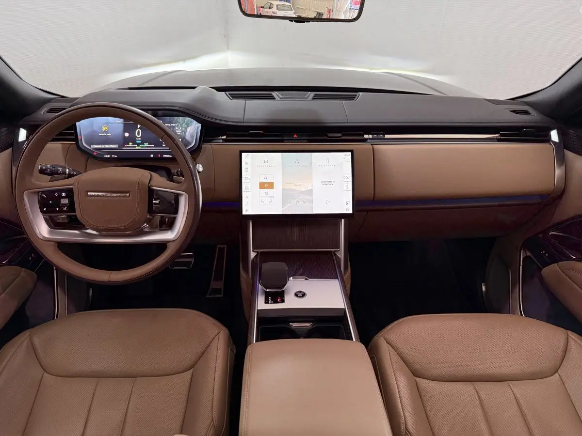 Vue intérieure avant du Range Rover PHEV 2024 avec tableau de bord noir et sièges cuir marron clair.