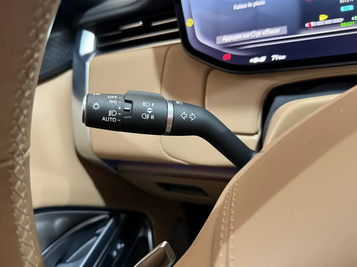 Gros plan sur la commande des feux et clignotants dans l’habitacle beige du Range Rover PHEV 2024 noir.